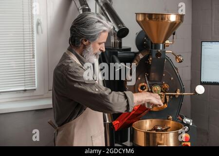 Leitender Mann verpackt Kaffeebohnen nach dem Rösten Stockfoto