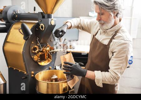 Leitender Mann verpackt Kaffeebohnen nach dem Rösten Stockfoto