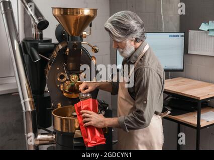 Leitender Mann verpackt Kaffeebohnen nach dem Rösten Stockfoto