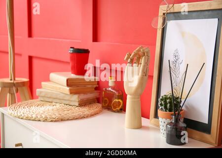 Holzhandwerk mit Zimmerpflanzen und Dekor auf Regal neben Farbwand Stockfoto