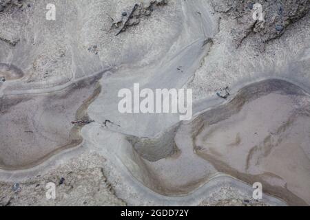 Mikroskalige geografische Merkmale im Schlamm nach einer Flußflut. Die Landschaft sieht aus wie Satellitenbilder, mit Schluchten, Flusstälern, Deltas und Schluchten. Stockfoto