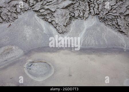 Mikroskalige geografische Merkmale im Schlamm nach einer Flußflut. Die Landschaft sieht aus wie Satellitenbilder, mit Schluchten, Flusstälern, Deltas und Schluchten. Stockfoto