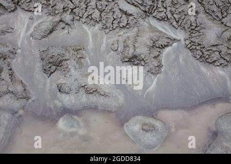 Mikroskalige geografische Merkmale im Schlamm nach einer Flußflut. Die Landschaft sieht aus wie Satellitenbilder, mit Schluchten, Flusstälern, Deltas und Schluchten. Stockfoto