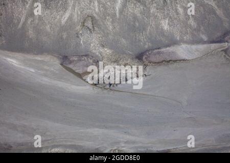 Mikroskalige geografische Merkmale im Schlamm nach einer Flußflut. Die Landschaft sieht aus wie Satellitenbilder, mit Schluchten, Flusstälern, Deltas und Schluchten. Stockfoto