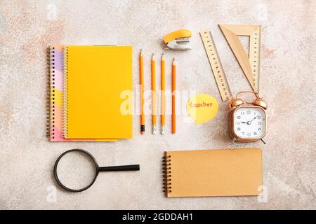 Papier mit TEXTLEHRERIN, Schreibwaren und Wecker auf grunge Hintergrund Stockfoto