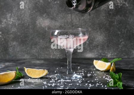 Gießen von Cocktail aus dem Shaker in Glas auf dunklem Hintergrund Stockfoto