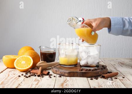 Frau, die Orangensaft in Glas mit Eis auf hellem Hintergrund, Nahaufnahme Stockfoto
