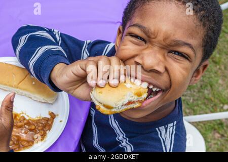 Miami Florida, Tropical Park, drogenfreie Jugendliche in der Stadt, DFYIT Picknick Schwarzer Junge beim Essen beißenden Hot Dog Bun, Stockfoto