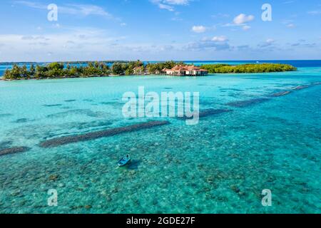Luftaufnahme der maledivischen Insel mit Holzhäusern und einem Boot im seichten Wasser im Indischen Ozean Stockfoto