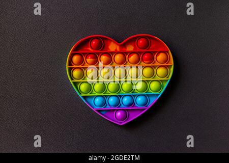 Bunte Sinnesspielzeug Fidget Push Pop es Herz auf schwarzem Hintergrund Stockfoto