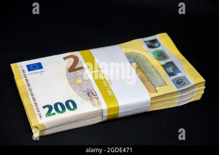 Auf schwarzem Hintergrund liegt ein Geldbündel mit 200-Euro-Banknoten Stockfoto