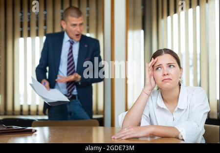 Emotionaler junger Chef beschimpft seine Sekretärin im Konferenzraum Stockfoto