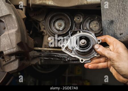 Ein Automechaniker zeigt die ausgebaute alte Motorpumpe Stockfoto