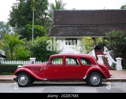 Klassisches rotes Fahrzeug mit Seitenansicht des alten Autos von der Seite des Fahrzeugs, das im Kolonialstil gebaut wurde Stockfoto