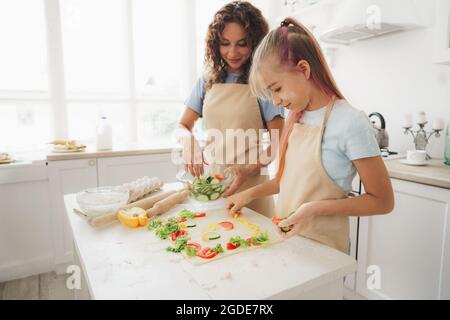 Nahaufnahme von Mutter und Tochter, die in der Küche vegane Pizza zubereiten Stockfoto