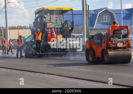 Tula, Russland - 16. Mai 2021: Prozess der Asphaltierung, Asphaltfertiger Maschine und zwei Straßenwalzen während der Straßenbauarbeiten, arbeiten auf der neuen Straße Stockfoto