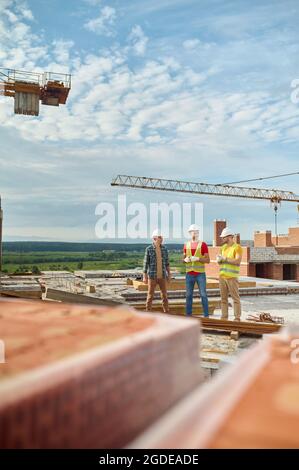 Drei Männer in Schutzhelmen stehen auf der Baustelle Stockfoto