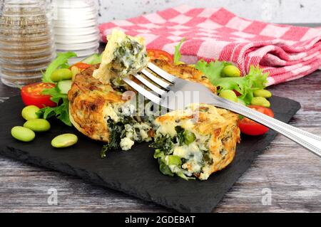 Spinat und Grünkohl-Quiche mit frischem Salat und Edamame-Bohnen auf einem Schieferbrett Stockfoto