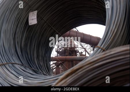 Hamburg, Deutschland. August 2021. Industrieanlagen hinter gestapelten Drahtspulen auf dem Gelände eines Stahlwerks der Firma ArcelorMittal GmbH. Quelle: Jonas Walzberg/dpa/Alamy Live News Stockfoto