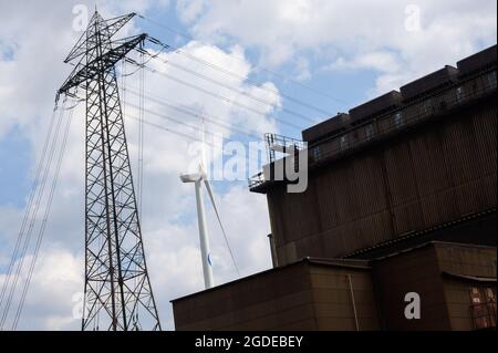 Hamburg, Deutschland. August 2021. Neben dem Standort eines Stahlwerks der Firma ArcelorMittal GmbH stehen ein Strompylon und eine Windkraftanlage. Quelle: Jonas Walzberg/dpa/Alamy Live News Stockfoto