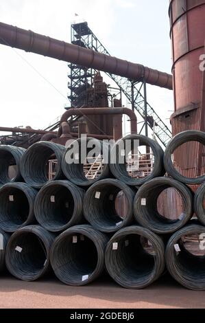 Hamburg, Deutschland. August 2021. Ein Hochofen hinter gestapelten Drahtwicklungen auf dem Gelände eines Stahlwerks der Firma ArcelorMittal GmbH. Quelle: Jonas Walzberg/dpa/Alamy Live News Stockfoto