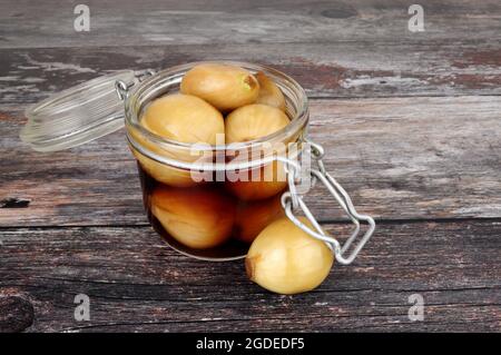 Glas-Vorratsglas gefüllt mit eingelegten Zwiebeln in Malzessig auf einem rustikalen Holzhintergrund Stockfoto