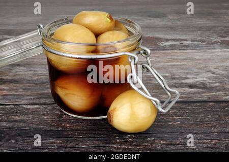 Glas-Vorratsglas gefüllt mit eingelegten Zwiebeln in Malzessig auf einem rustikalen Holzhintergrund Stockfoto