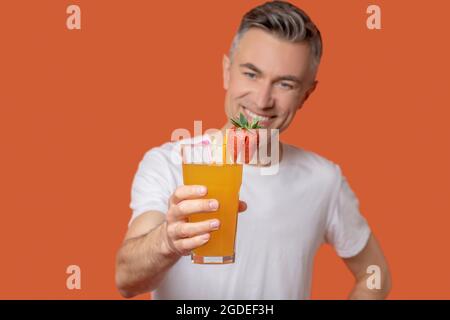 Erfolgreicher Mann, der ein Glas frischen Saft aushält Stockfoto