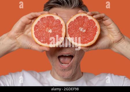 Nahaufnahme von mans Gesicht und Hälften von Grapeuit Stockfoto