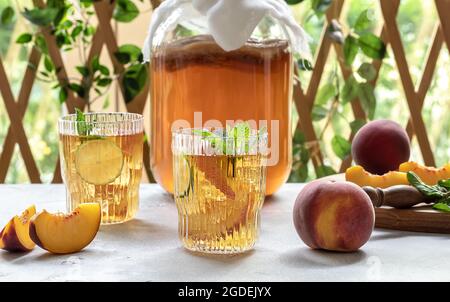 Hausgemachte Gärung. Kombucha-Tee leicht alkoholisches, leicht brausendes Getränk mit Pfirsich und Limette. Stockfoto