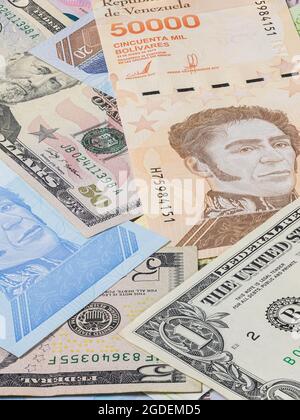 Das fast wertlose venezolanische Geld auf einem Haufen zwischen den starken US-Dollar. Bolivares oder Bolivar, die Währung Venezuelas. Inflation hält an für Stockfoto