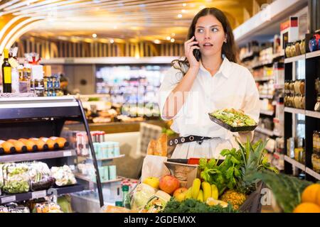 Junge Frau, die beim Einkaufen telefoniert Stockfoto
