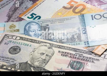 Schließen Sie bis zu 100 Gourde der Republik Haiti zwischen 50 US-Dollar und 50 Euro-Banknoten. Hundert Gourde-Banknoten des karibischen Landes Hait Stockfoto