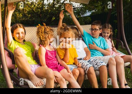 Kinder sitzen auf einer großen Schaukel im Hinterhof Stockfoto