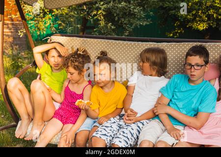 Kinder sitzen auf einer großen Schaukel im Hinterhof Stockfoto