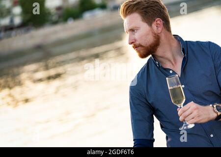 Porträt eines hübschen Mannes, der Champagner im Freien hält Stockfoto