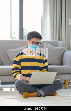 Asiatische Kursteilnehmer mit einer Menge Bücher und Laptop Vorbereitung auf die Prüfung zu Hause Stockfoto
