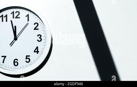 Das weiße Ziffernblatt einer Wanduhr zeigt die Zeit an. Es ist nahe bei 12 Uhr. Der neueste Bericht des Atomwissenschaftlers zeigt die Weltuntergangsuhr 100 secon Stockfoto