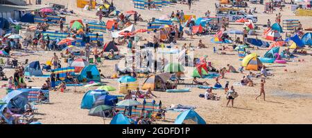 Ein Panoramabild Fistral Beach in Newquay in Cornwall. Urlaubsreisende drängen sich zum Fistral Beach, um die intensive Sommersonne zu genießen. Stockfoto