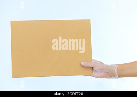 Eine Frau hält in medizinischen Handschuhen einen Papierumschlag Amazon auf weißem Hintergrund Expresslieferung der Kurier brachte das Paket mit Stockfoto