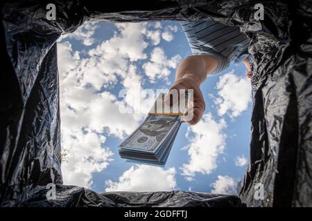 Wegwerfen von Dollars im Papierkorb. Überschüssiges Bargeld loswerden und auf Bargeldzahlungen umsteigen. Das Konzept der Inflation. Stockfoto
