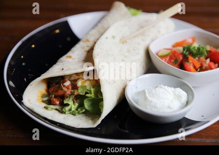 Mexikanische Burritos auf einem Teller mit Tomatensalat Stockfoto