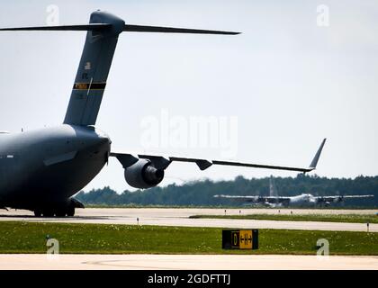 Ein C-17-Flugzeug von der Pittsburgh Air Reserve Station, Pennsylvania, Taxis an der Youngstown Air Reserve Station, Ohio, während ein 910th Airlift Wing C-130H Hercules im Hintergrund abhebt, 8. August 2021. Die C-17 war eine von drei Flugzeugen, die die lokale Start- und Landebahn und den nicht überlasteten Luftraum für Schulungen genutzt haben. (USA Luftwaffe Foto/Staff Sgt. Noah J. Tancer) Stockfoto