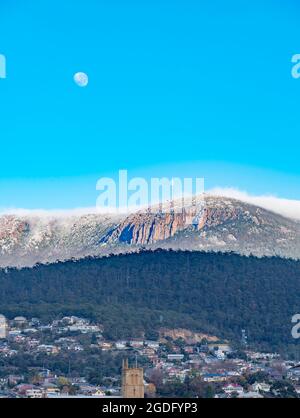 Mit dem Mond noch oben rollt eine Decke aus Wolken am frühen Morgen über Kunanyi (Mount Wellington) in Richtung Hobart, der Hauptstadt Tasmaniens in Australien Stockfoto
