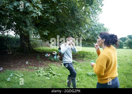 Paar spielen mit Seifenblasen in Feld Stockfoto