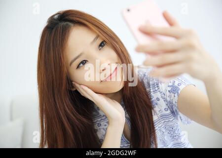 Junge schöne Frau Foto Selfie in weißem Ton Stockfoto