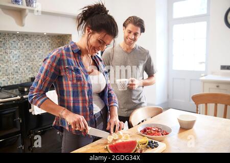 Paar chatten während Schneiden frisches Obst am Küchentisch Stockfoto