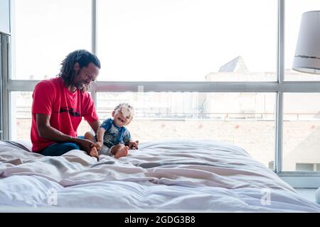 Vater und Sohn spielen auf Bett Stockfoto