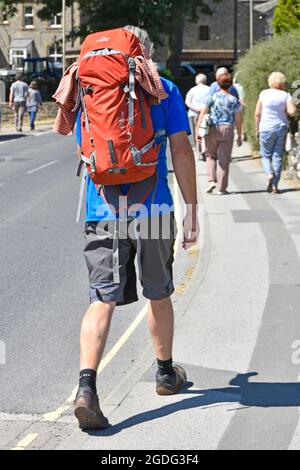 Close up back view Dales Walker Mann trägt großen Rucksack in Shorts & Wanderstiefel auf dem Bürgersteig in Grassington Wharfedale North Yorkshire England UK Stockfoto