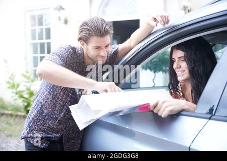 Paar in geparkten Auto vor der Eingangstür an der Faltung Karte suchen Stockfoto